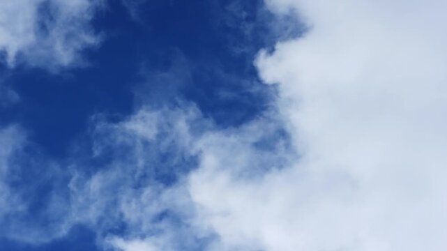 Zoom cinematic timelapse video of white cloud formations on a windy day in deep blue sky