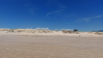 White sand dunes on the beach with blue sky and white clouds