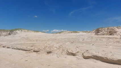 White sand dunes on the beach with blue sky and white clouds