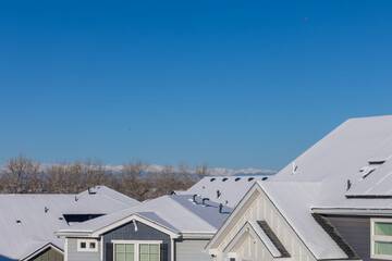 Snow-covered roofs in a Colorado neighborhood with the mountain range in the distance