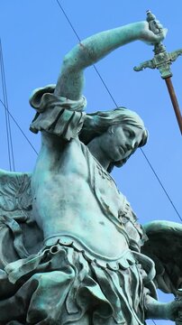 powerful bronze archangel michael statue crowning castel sant angelo rome winged figure mid motion clear blue sky defines sant'angelo up close italy roman empire emperor 