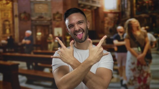 Hispanic man makes rock gesture in a church embodying faith and joy, showing youthful energy and indoor vibrancy, highlighting cultural blend of modernity and tradition.