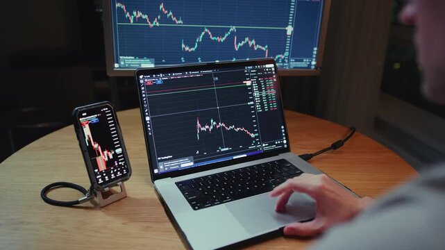 Man stock trader in home office. Male analyzes terminal, trades stocks on crypto market. Quotes from Bitcoin Ethereum, or funds. Candlestick or trading charts, price action on the laptop screen. Night