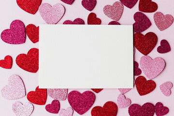 Valentines day card mockup. Empty greeting card flat lay with stylish pink and red glitter hearts on pink paper background. Happy Valentine's day postcard with space for text