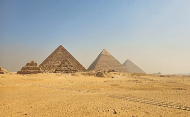 Wide panoramic view of the Great Pyramids of Giza under a clear blue sky, showcasing ancient Egyptian architecture and the vast desert landscape near Cairo, Egypt.