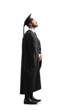 Full length shot of a man in a black graduation gown and cap looking up
