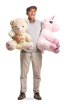 Smiling senior man standing with a teddy bear and a unicorn toy