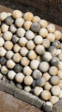 weathered stone cannonballs form precise pyramid patterned brick paving within low border military display ancient remnants historic castel sant'angelo rome italy history 