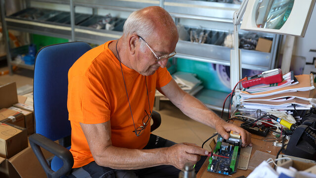 Professional technician analyzing printed circuit boards under bright lights in testing lab