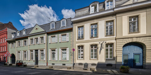 Obraz premium A row of colorful historic townhouses with shutters at Freiheit in Cologne-Muelheim under a bright blue sky