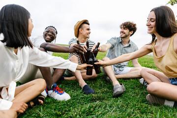 Young group of diverse friends having fun drinking beer during summer vacation, relaxing together...