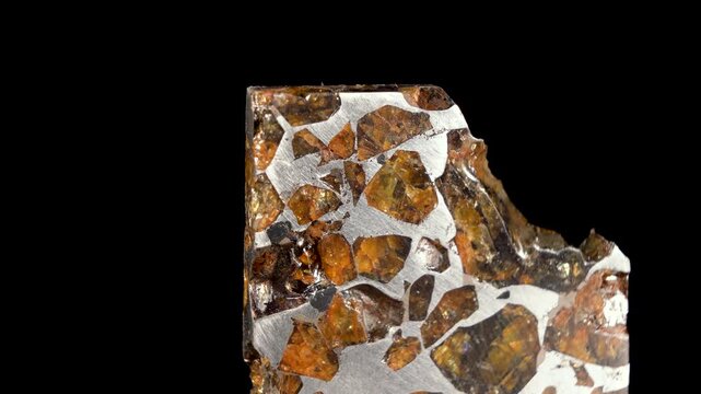 Rotating Of An Iron Meteorite. black background on a mirror base. Close-up. Macro