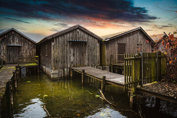 Wooden pier with old fisherman's boat house in the early misty morning at lake