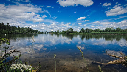 Peaceful picturesque mesmerizing atmospheric landscape at lake with on summer day with blus sky and clouds mirrow reflected in lake water