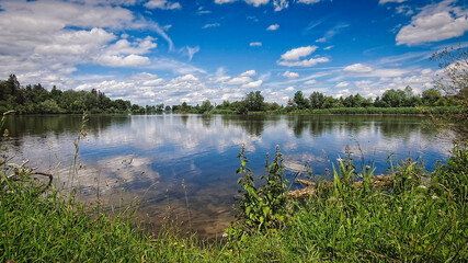 Obraz premium Peaceful picturesque mesmerizing atmospheric landscape at lake with on summer day with blus sky and clouds mirrow reflected in lake water