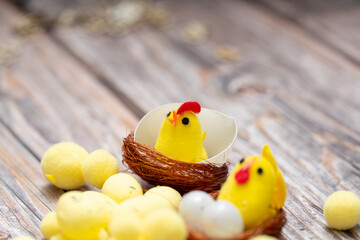 Decorative chicks in nests with colorful eggs on wooden surface during spring activity