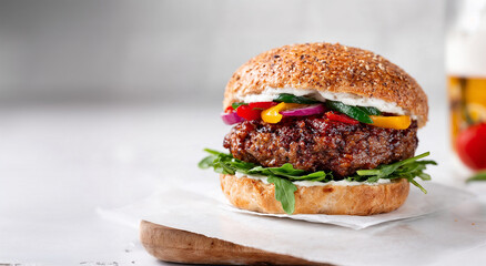 Juicy hamburger with colorful peppers and greens on wooden board  