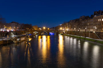 Obraz premium Night view of the Seine River with bridge and city lights in Paris, France