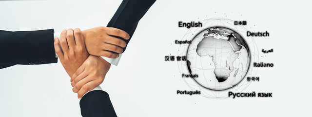 Close-up of diverse hands interlocking over a globe marked with various language labels,...