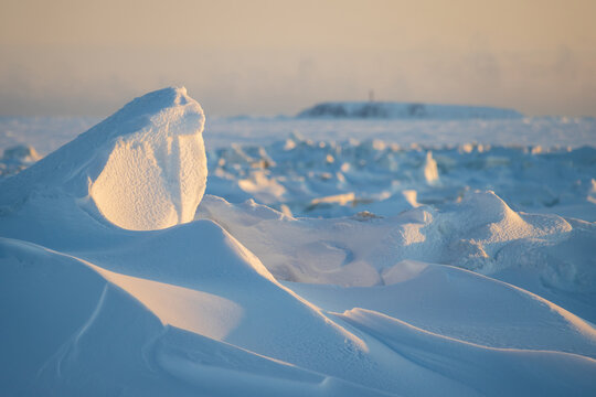Winter arctic landscape. Cold frosty winter weather. Harsh polar climate. Ice hummocks on the frozen sea in the Arctic. View of snow and ice at sunset. Picturesque nature of the Arctic. Far North.