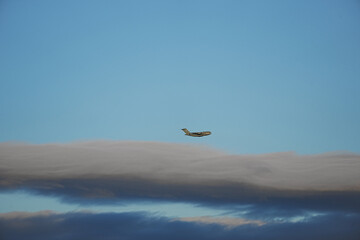 Fototapeta premium A C-17 Globemaster III military transport aircraft is in flight above a layer of clouds in the Nevada desert.