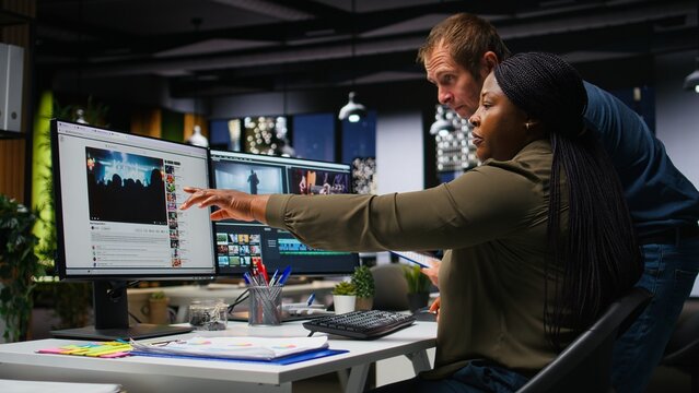 Team of multiethnic videographers editing video shoot in post production, using modern tech and editing software for a creative video project. Modern workspace with dual monitors. Camera A.