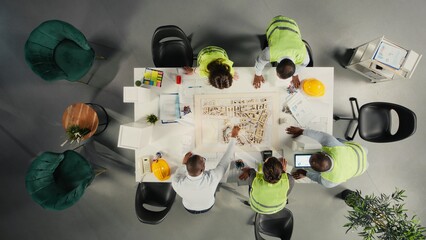 Top down view of doctors team in a collaborative meeting discussing therapy, diagnostics and clinical coordination. Modern healthcare staff focuses on communication and patient health. © DC Studio