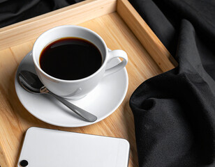 Overhead View of Coffee Cup, Saucer, Spoon, Phone on Wooden Tray, Black Fabric.