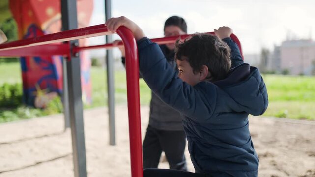 Two boys exercising and playing on playground monkey bars