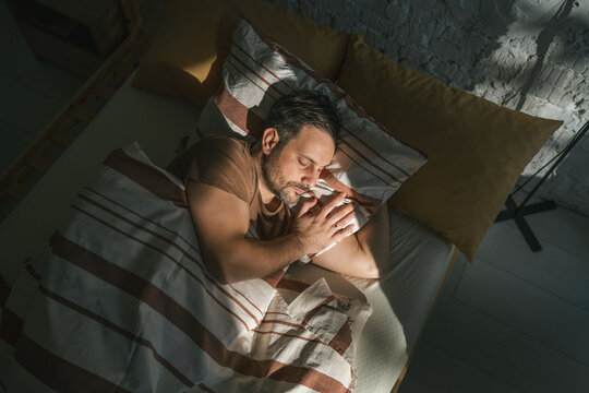 Man sleeping peacefully in bed experiencing deep relaxation