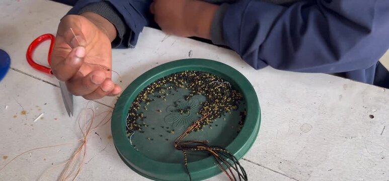 Close up of black hands threading beads to make bracelets or neckless