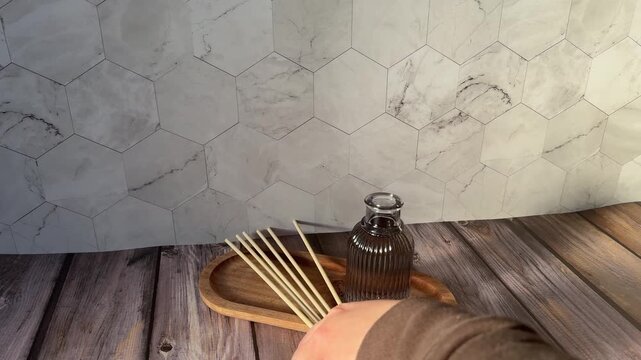 Hands Placing Wooden Sticks into New Reed Diffuser