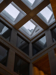 Fototapeta premium Modern building atrium interior with geometric skylights covered in snow, concrete and wood architecture looking upward