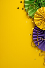 Bright vertical Mardi Gras colors with green, purple and yellow fans, beads, and confetti create a festive celebration mood on a vibrant yellow background © ActionGP