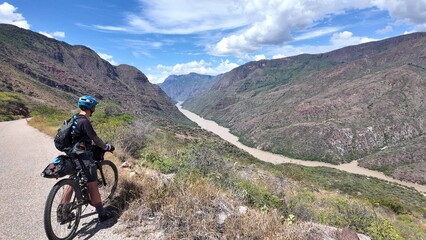 Fototapeta premium Mountain biker overlooking a canyon river Sogamoso Colombia during an adventure ride. Concept of adventure travel, outdoor cycling, connection with nature
