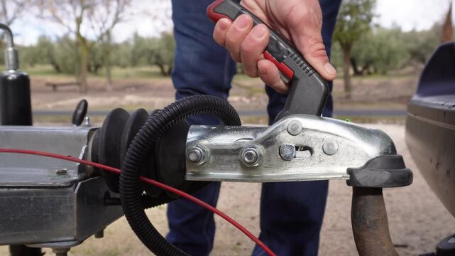 Closeup of a man's hands attaching a trailer coupling to a vehicle towbar. The process of connecting the tow ball to ensure a secure haul