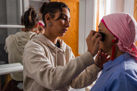 Daughter helping mother with cancer applying makeup
