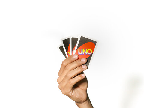 Semarang, Indonesia - January 1, 2026: Man's hand holding Uno game cards isolated on white background