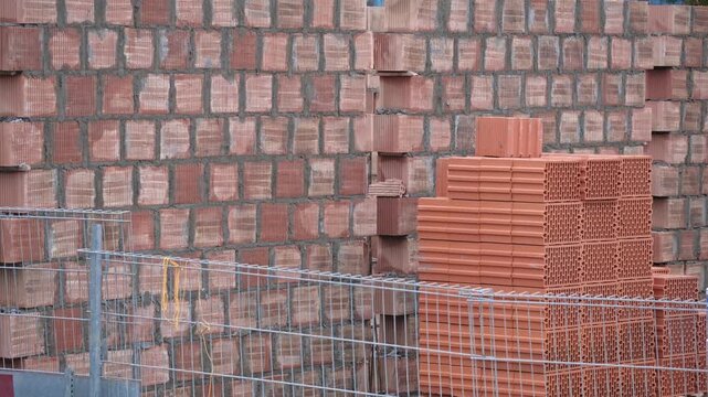 Construction Site with Stack of Red Clay Cinderblock Bricks and Used for Building Load Bearing Wall