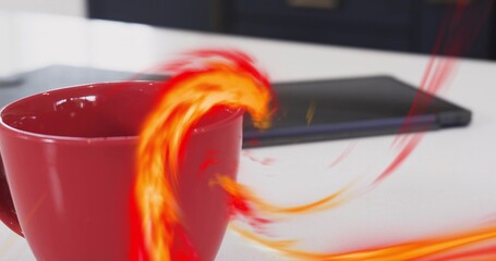 Sitting red ceramic coffee mug resting on white tabletop in kitchen, with tablet and flame trails