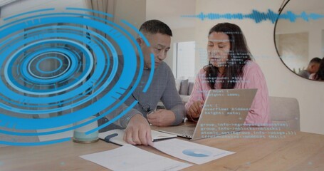 Reviewing two colleagues in pink shirt and gray sweater examining laptop and AR charts at home