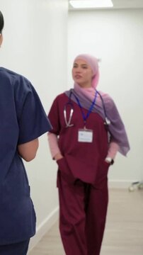 Vertical video: Walking down corridor nurse in maroon scrubs giving update and showing stethoscope