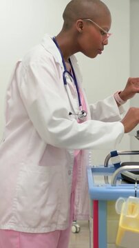 Vertical video: Picking up glasses woman in pink scrubs coat preparing cart near MRI CT X-RAY signs