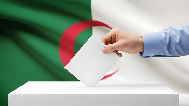 Hand casting a vote into a ballot box with the Algerian flag in the background, symbolizing elections.