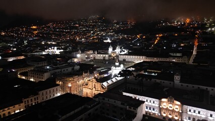 Fototapeta premium Aerial Night View of Quito Historic Center, Ecuador. Stunning aerial drone footage of Quito’s Historic Center at night, Ecuador. Illuminated colonial churches, historic buildings, and narro