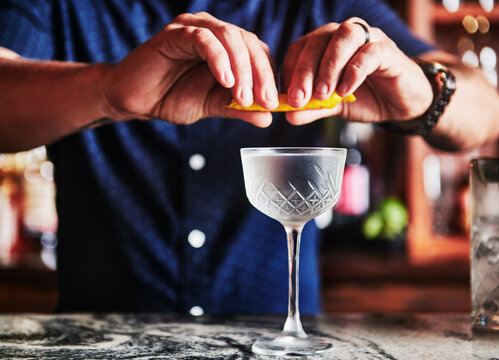 squeezing a lemon twist over a vodka cocktail 