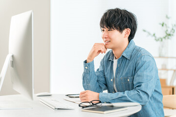 A man using a computer at home to telework, online seminar, side job, video editing