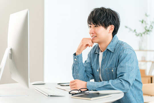 A man using a computer at home to telework, online seminar, side job, video editing
