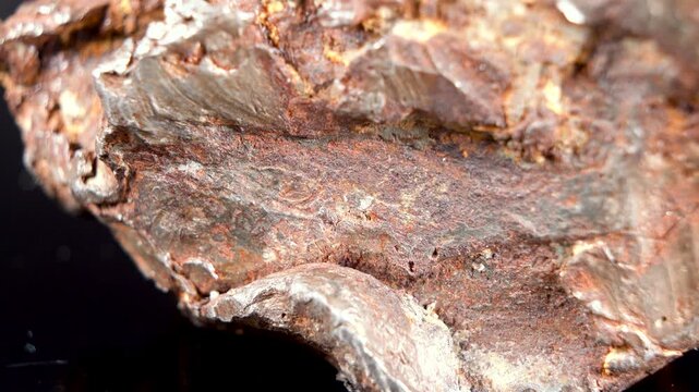 Rotating Of An Iron Meteorite. black background on a mirror base. Close-up. Macro. Rust on the surface