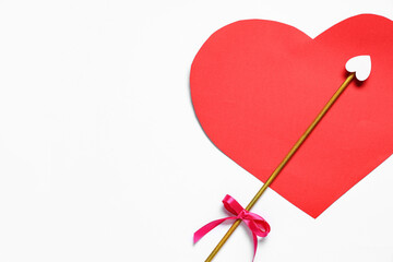 Naklejka premium Cupid's arrow and red paper heart on light background. Valentine's Day celebration
